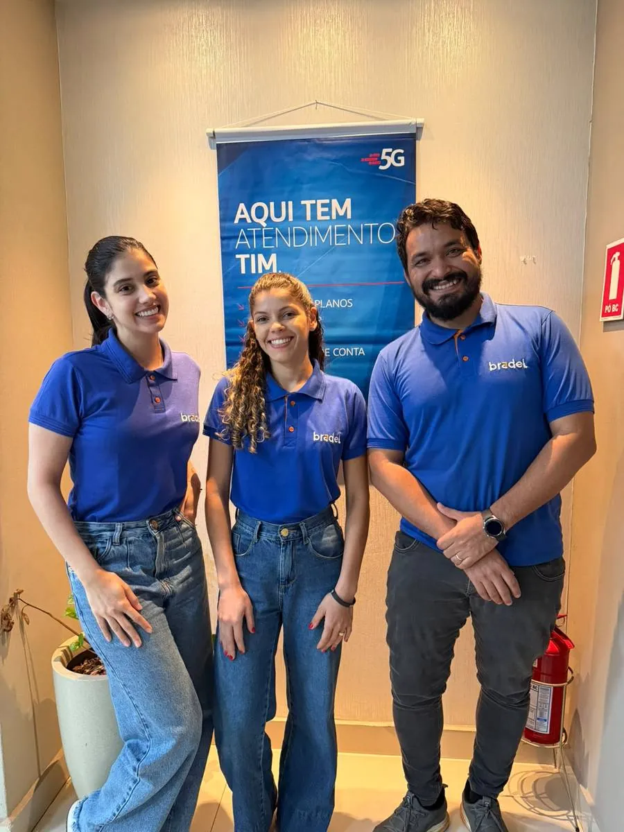 Equipe Bradel ao lado de banner TIM